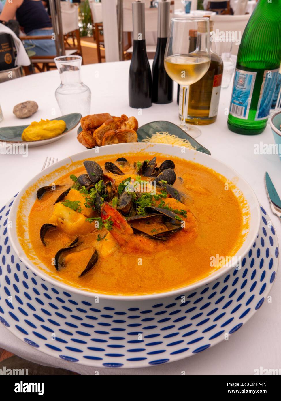 Table ready with bouillabaisse soup in a restaurant. Delicious fish soup with fish fillet clams, other shellfish and vegetables. Stock Photo