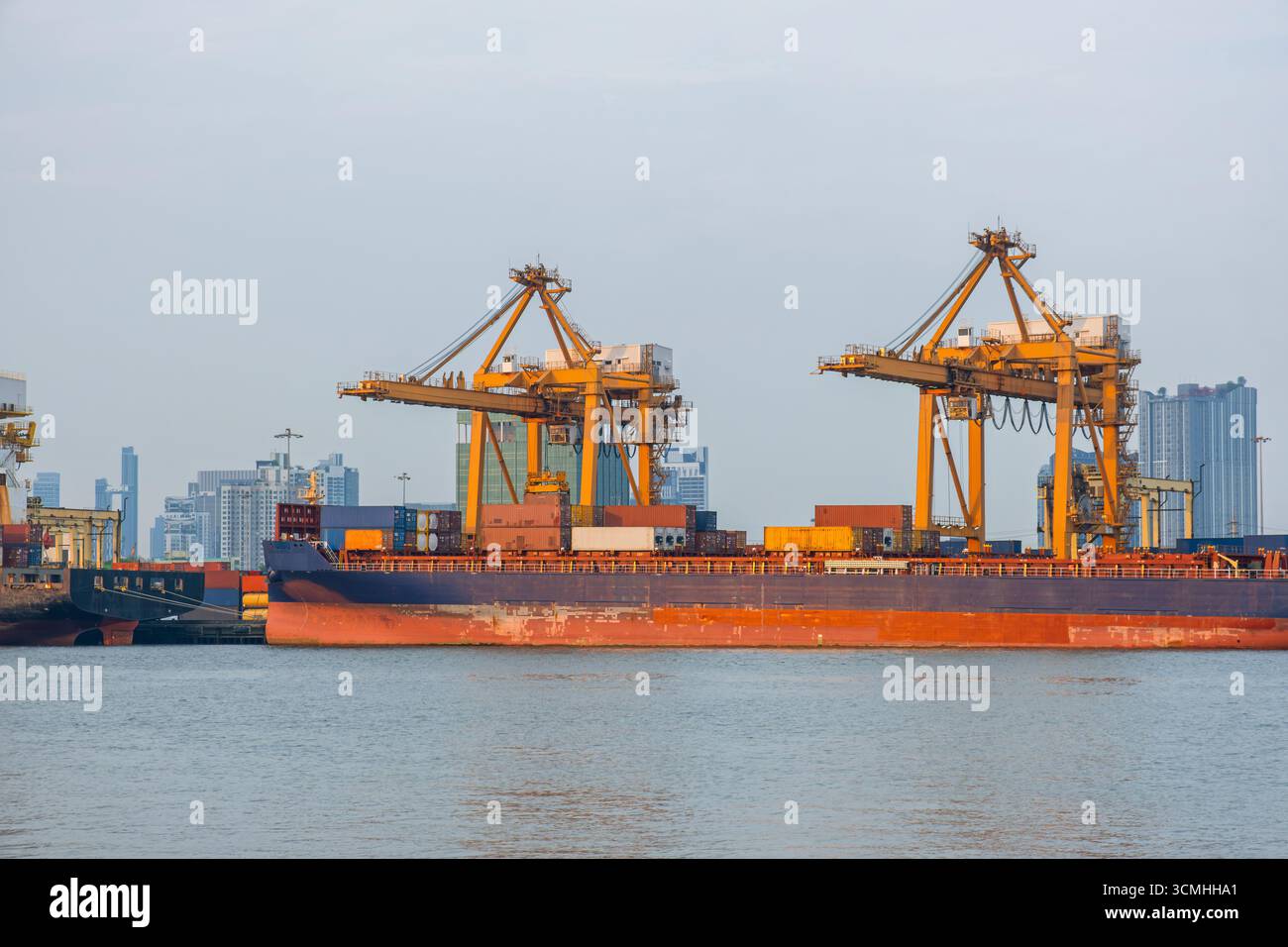 Large container cargo ship docked at port terminal with yellow cranes ...