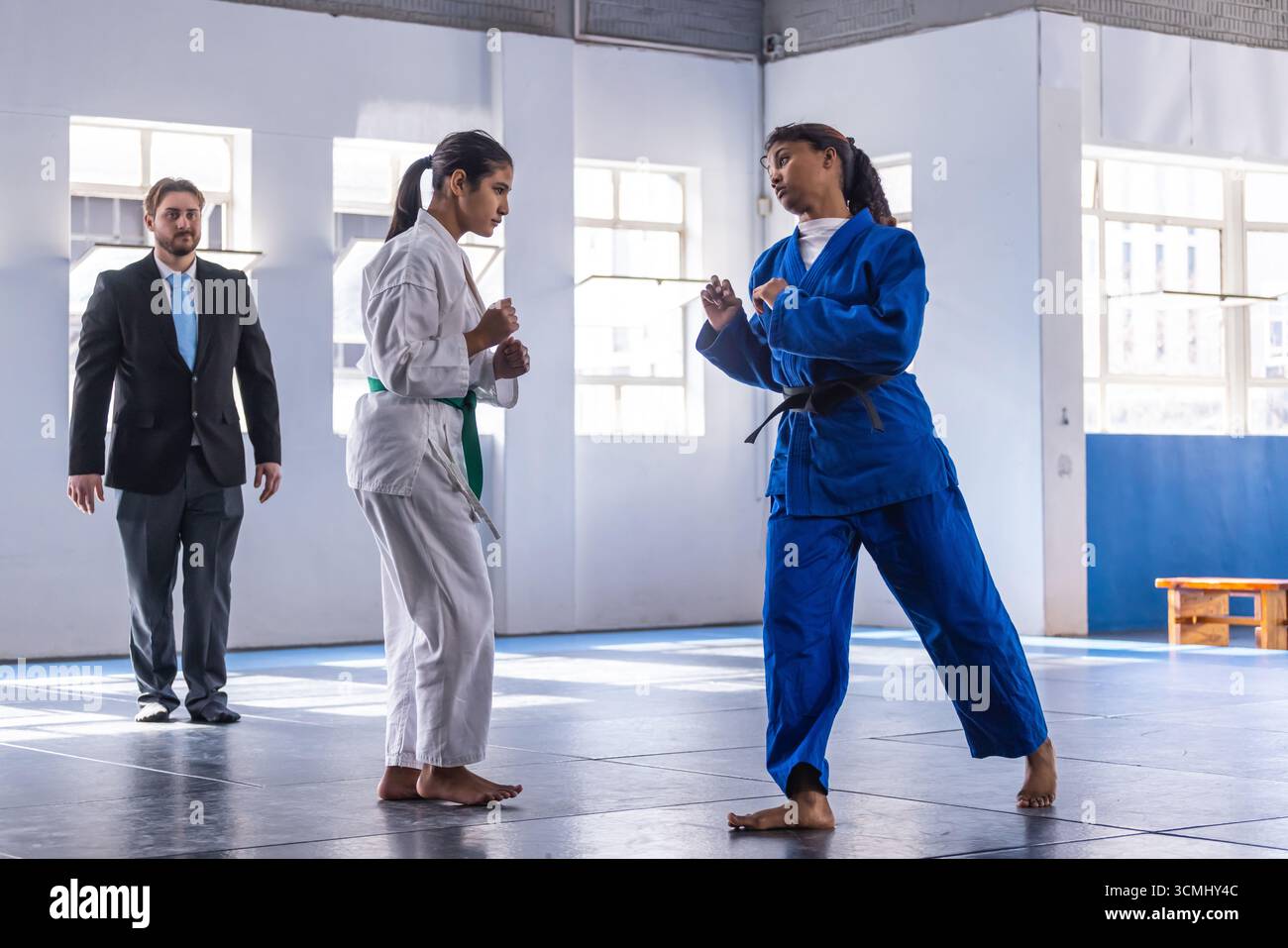 Diverse teenage female athletes sparring in martial arts gym with white, blue gis, copy space Stock Photo