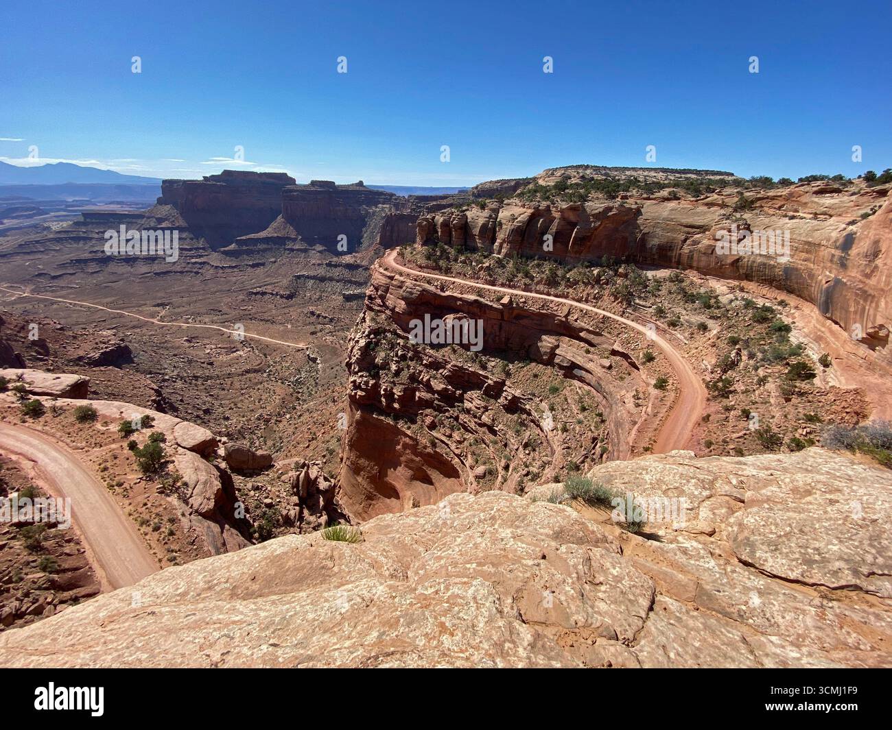 A sweeping landscape view from Shafer Trail Viepoint, looking down into the canyon and dirt road leading to the valley floor,  at the vast high desert - Smartphone Captured Stock Image
