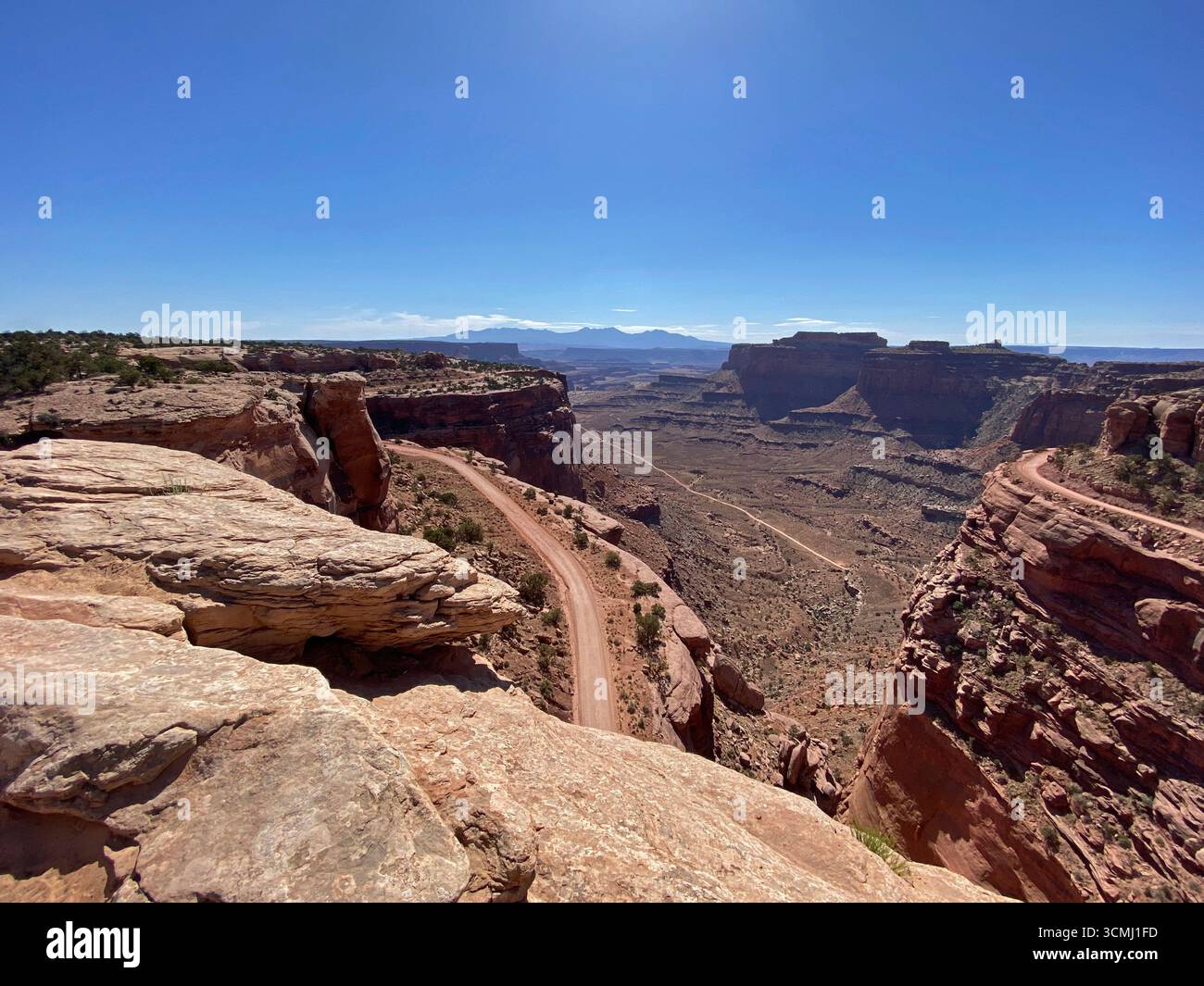 A sweeping landscape view from Shafer Trail Viepoint, looking down into the canyon and dirt road leading to the valley floor,  at the vast high desert - Smartphone Captured Stock Image