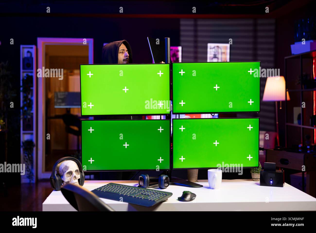 Hacker using chroma key PC displays, coding malware designed to exploit network backdoors. Rogue engineer using isolated screen multi monitor setup to bypass password protections Stock Photo
