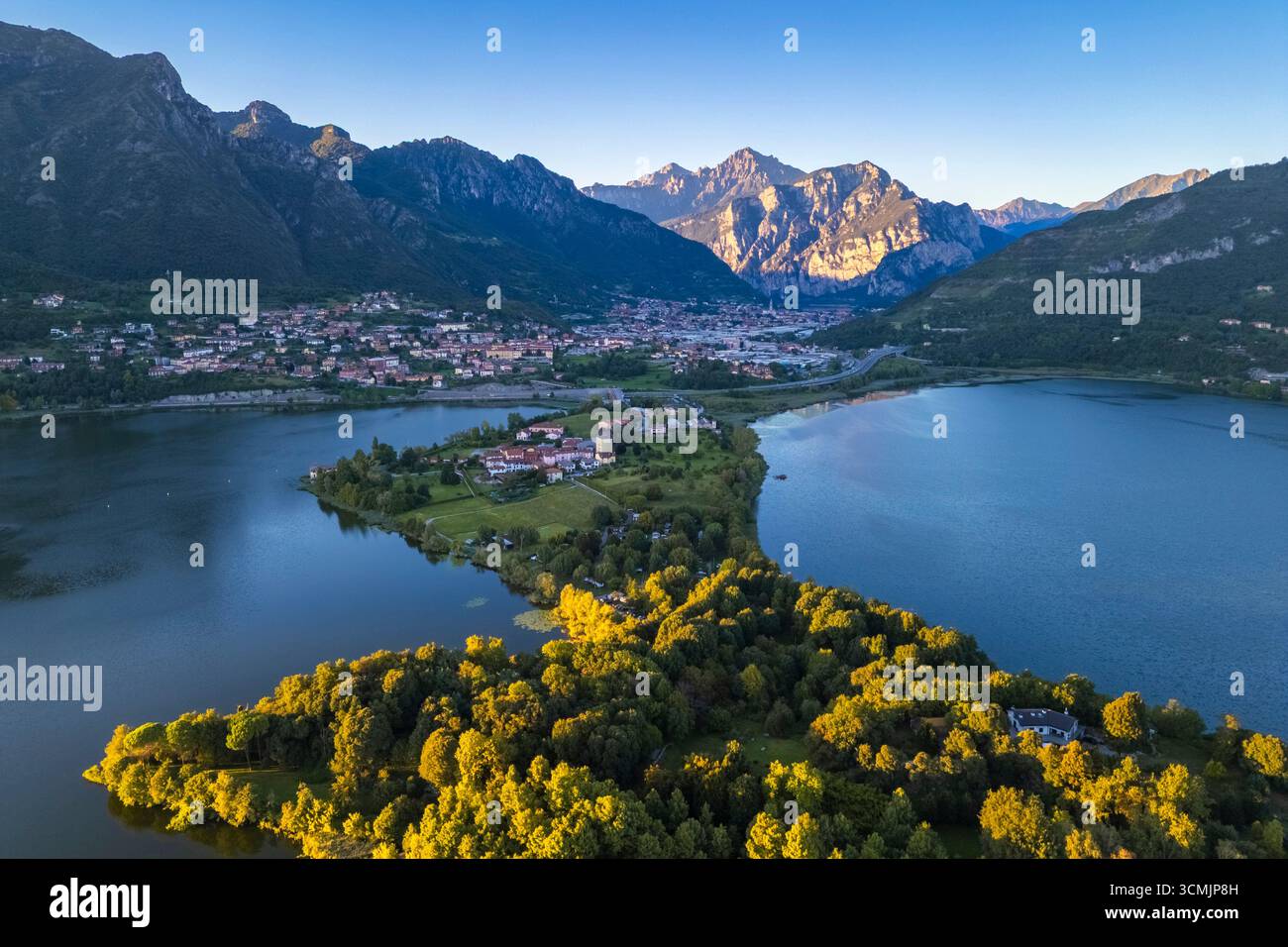 View of a summer sunset on the isthmus that divides lake Annone with Civate village and Lecco mountains. Annone di Brianza, Lecco province, Lombardy, Stock Photo