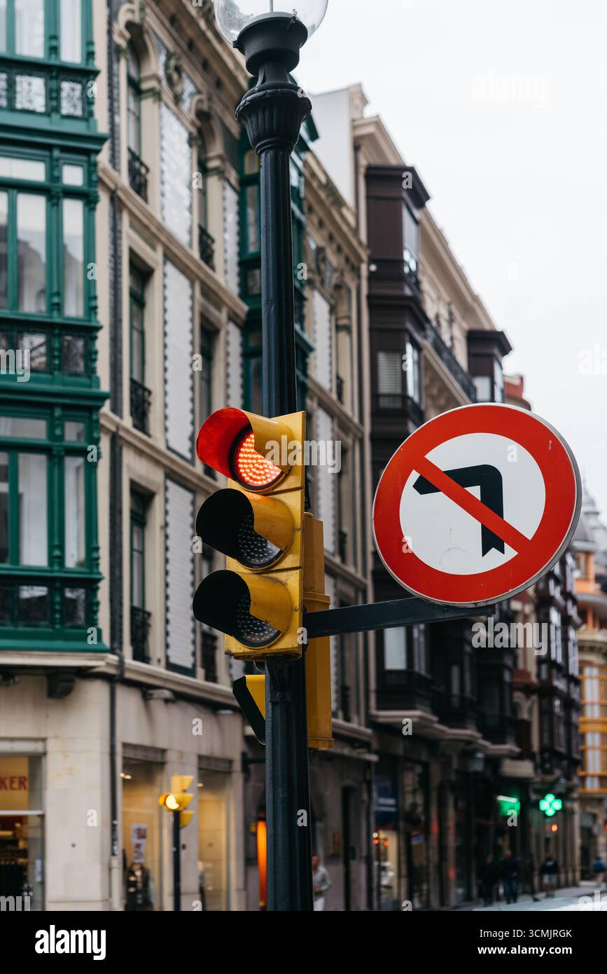 Traffic light showing red and yellow signals with no left turn sign on city street, surrounded by historic architecture, highlighting urban navigation Stock Photo
