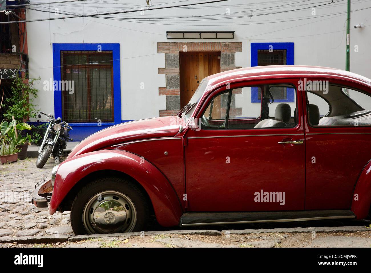A classic red Volkswagen Beetle parked on a cobblestone street in the ...
