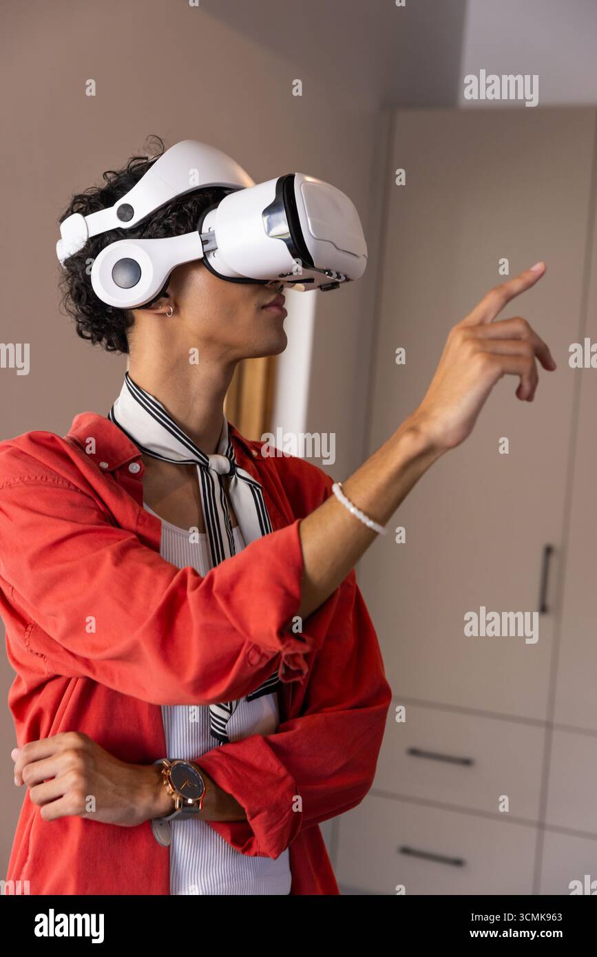 Virtual reality headset displaying interface, hand pointing forward in living room Stock Photo
