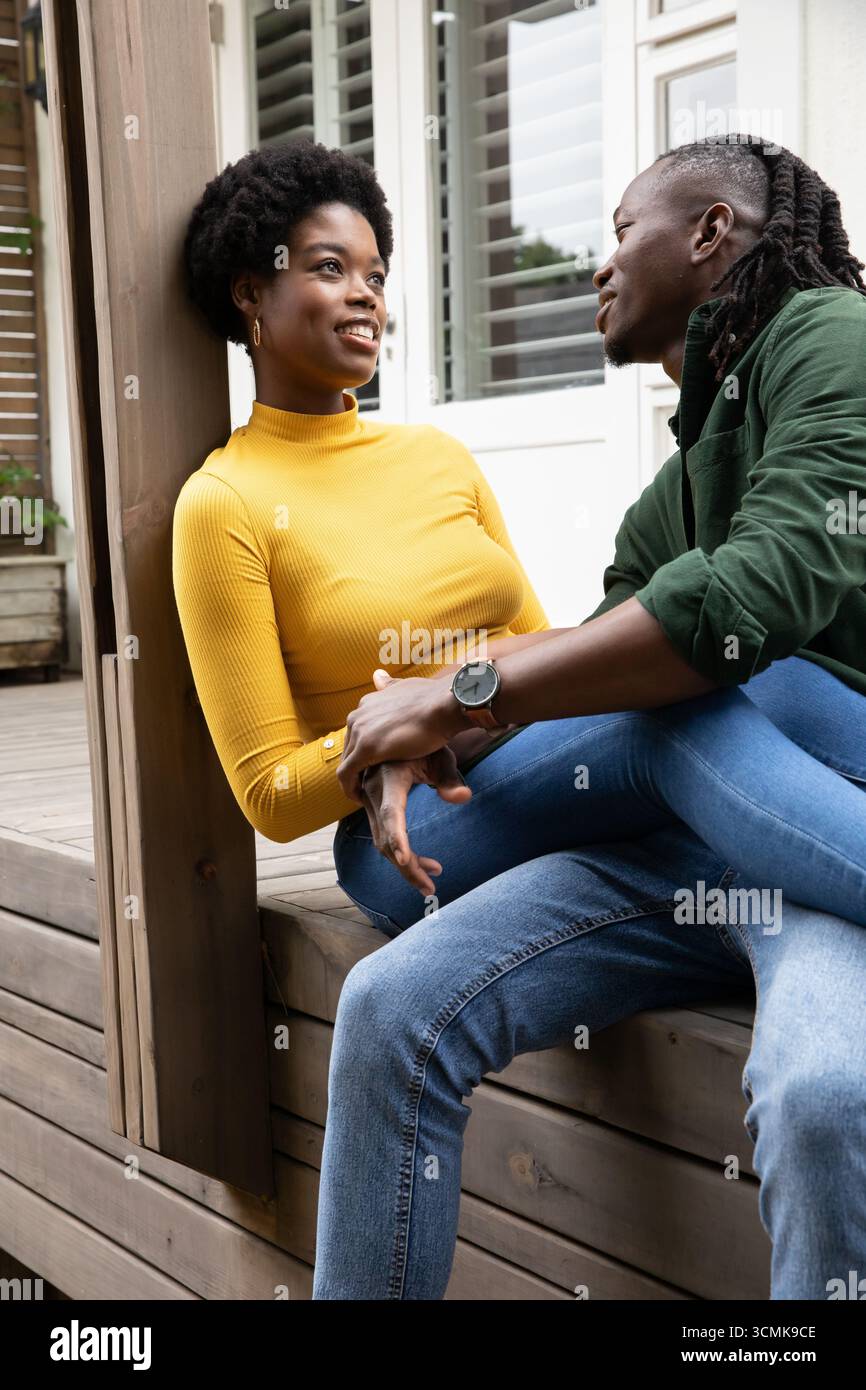 African american couple holding hands and gazing at each other on porch ...