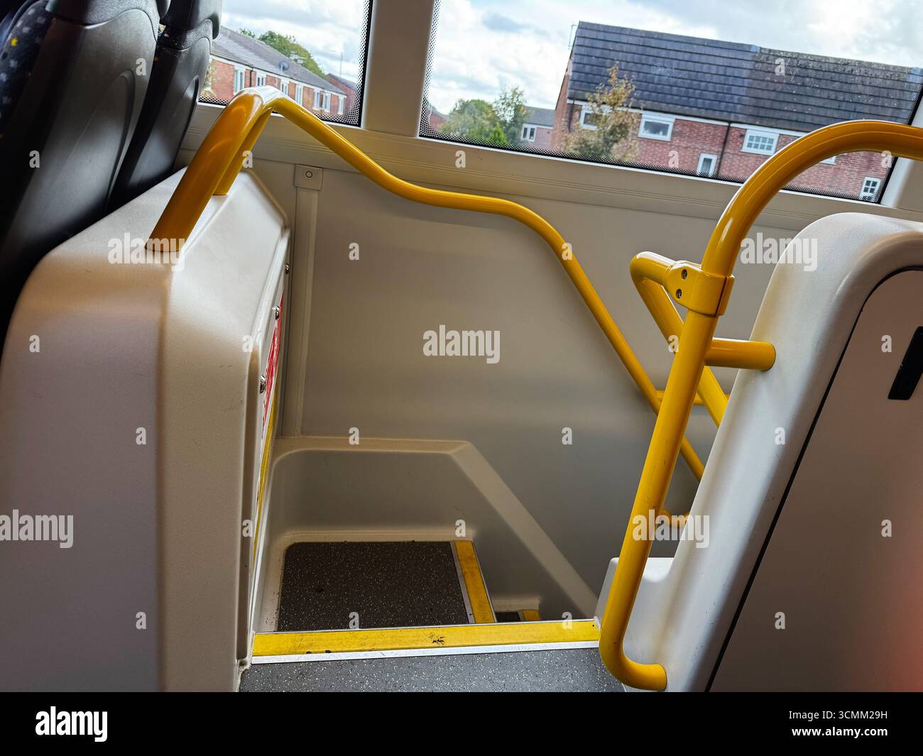 A yellow handrail staircase inside a double-decker bus with exterior ...
