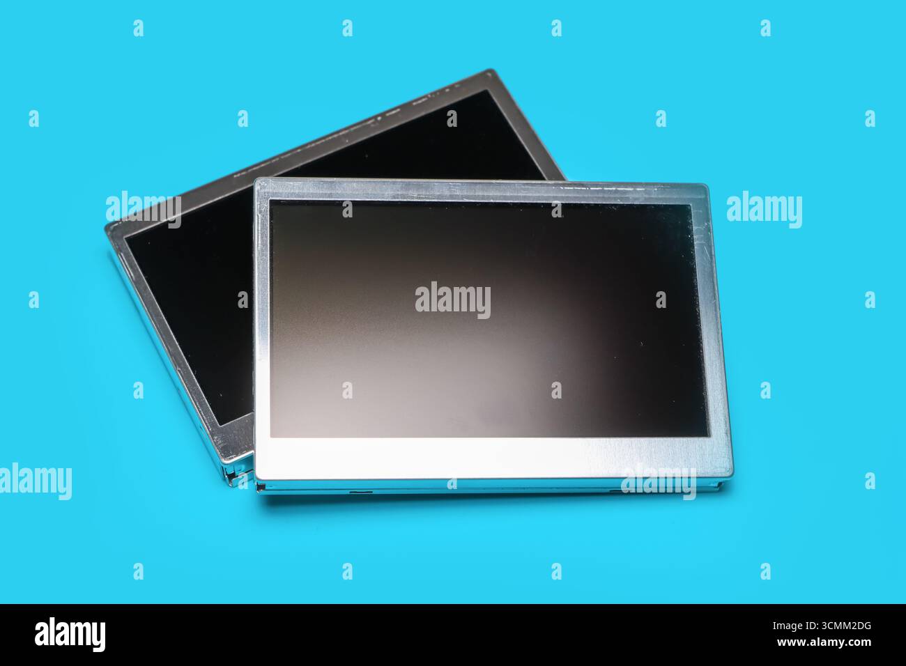 Two old automotive LCD display spares on blue background. Stock Photo