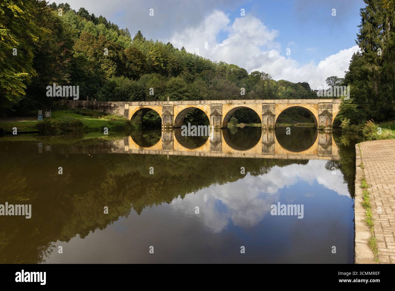 Saint Nicholas Bridge over the Semois River, at Chiny, in the Ardennes Forest in Belgium. Calm early morning scene, with the kayak launch area to the - Stock Image