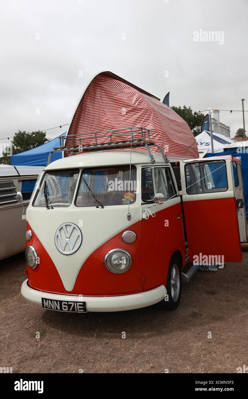 Red and white Vintage Vw Campervan with roof up parked at Rally in Paignton Stock Photo