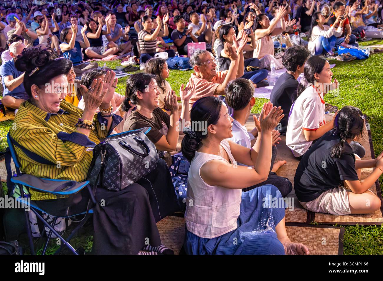 Thai family and audience enjoying open air concert with Royal Bangkok Symphony Orchestra in Lumphini Park, Bangkok, Thailand Stock Photo