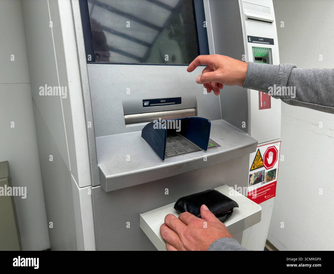 Bavaria, Germany - September 17, 2025: A man withdraws cash from an ATM ...