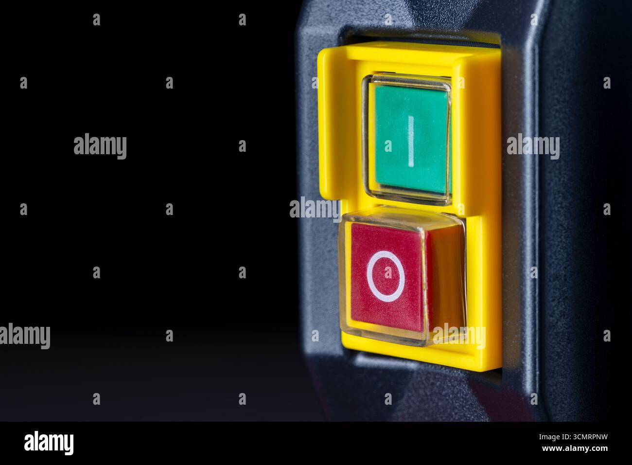 An electronic panel on an industrial machine with a green power button and a red power button. Electrical power switches on the yellow panel, close up Stock Photo