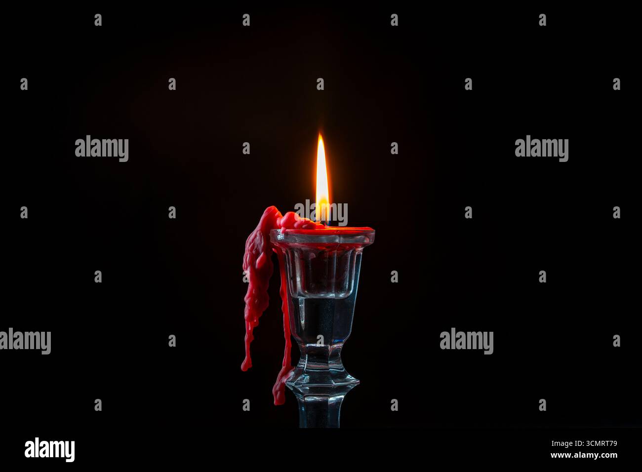 Glass candlestick with red burning candle on black background, close up Stock Photo