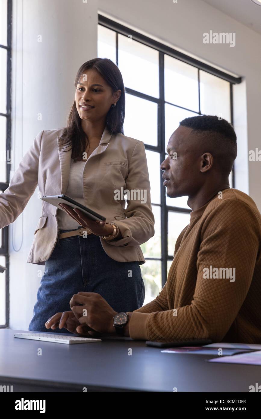Diverse coworkers in business attire working on tablet and keyboard at ...