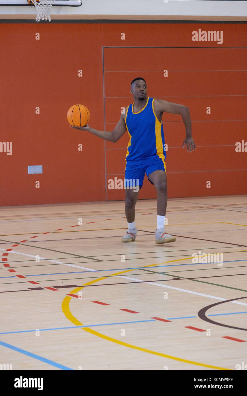 Male basketball player standing on court with markings by wall holding ...