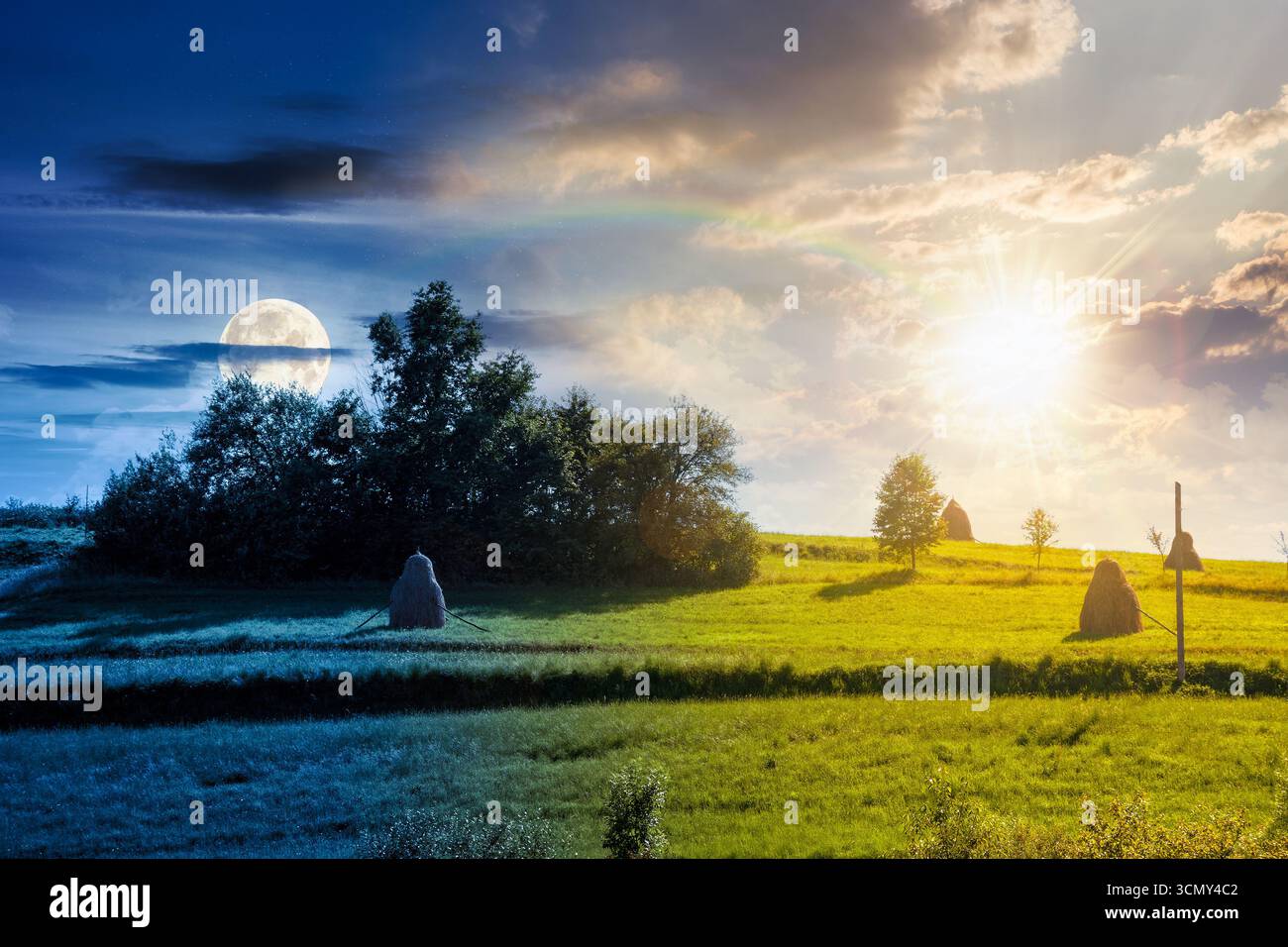 countryside landscape in mid summer. day and night time change concept. beautiful scenery with haystack on and rural field on steep green hill under b Stock Photo