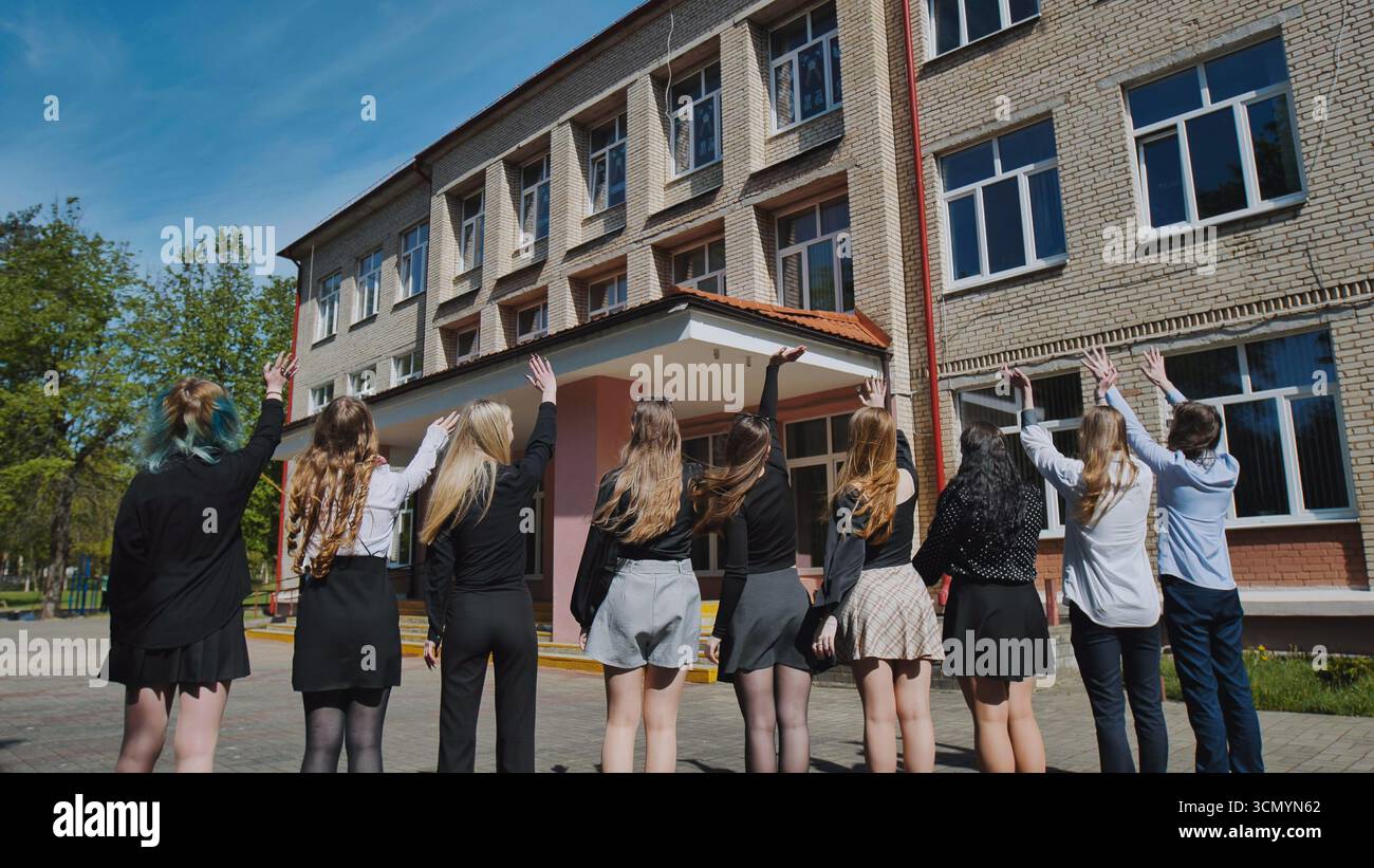 Group of happy students waving goodbye to their school on the last day ...
