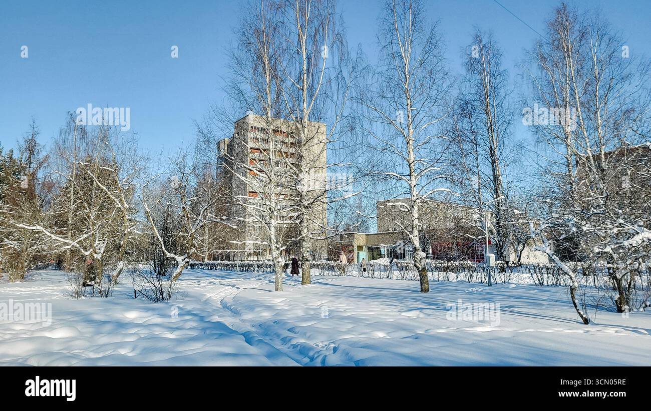 Koryazhma, Russia - 2024-02-15 - View of a panel building through a snow-covered park on a sunny frosty winter day Stock Photo