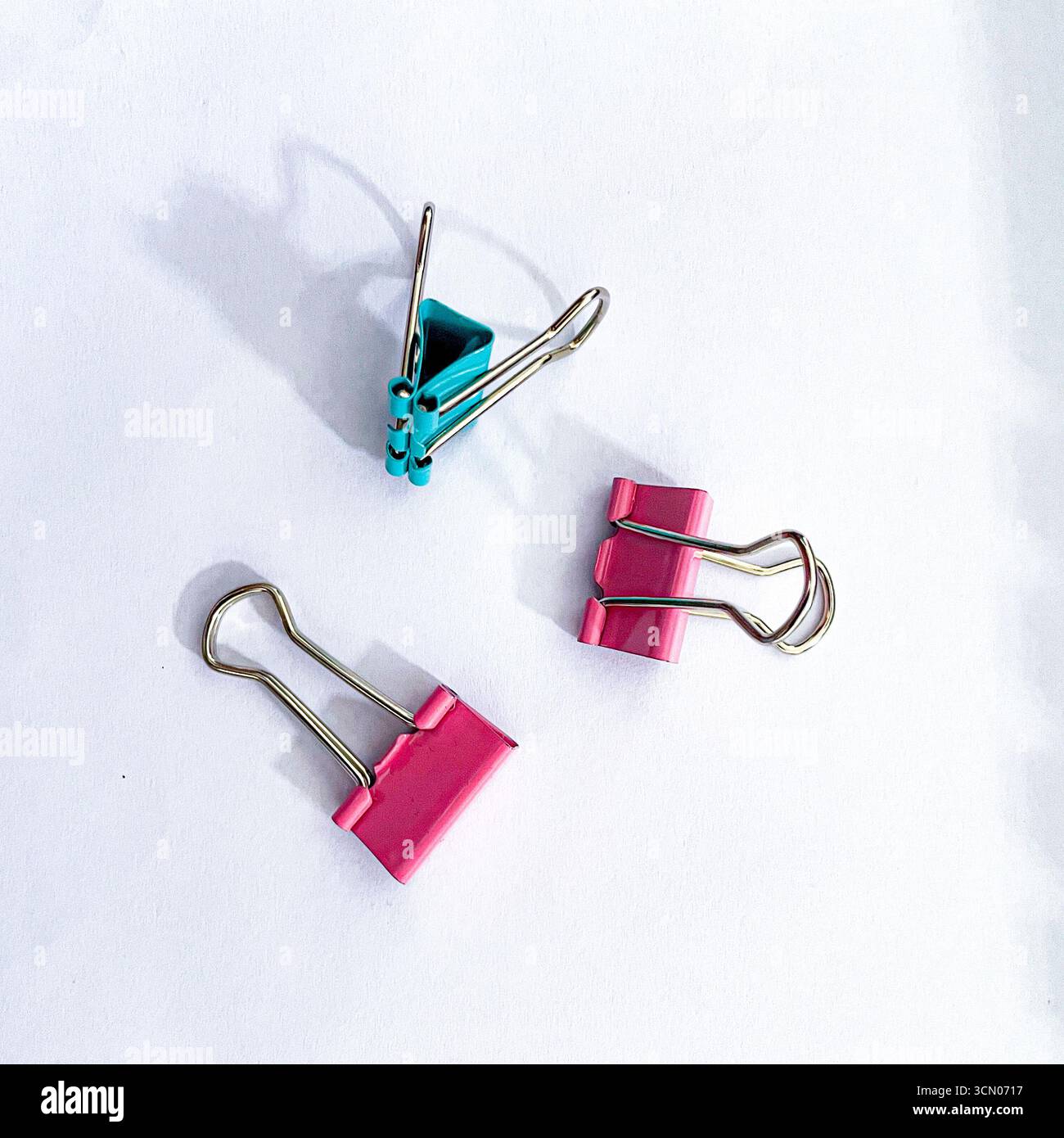 arrangement of small binder paper clips in various colors on a white background - Smartphone Captured Stock Image