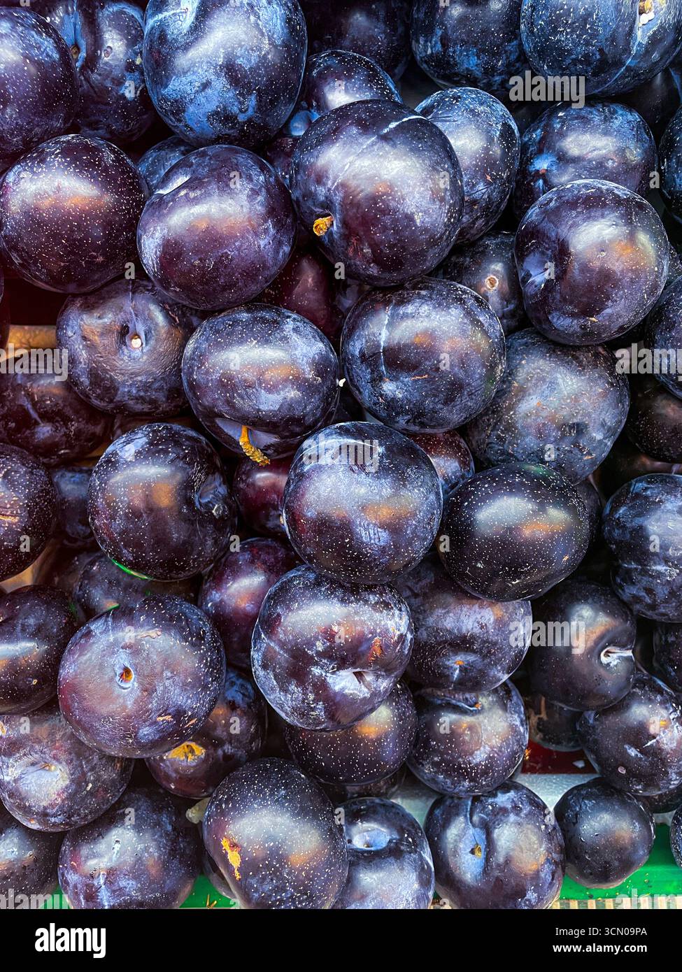 close up and freshly picked plum fruit stacked on store as food background - Smartphone Captured Stock Image