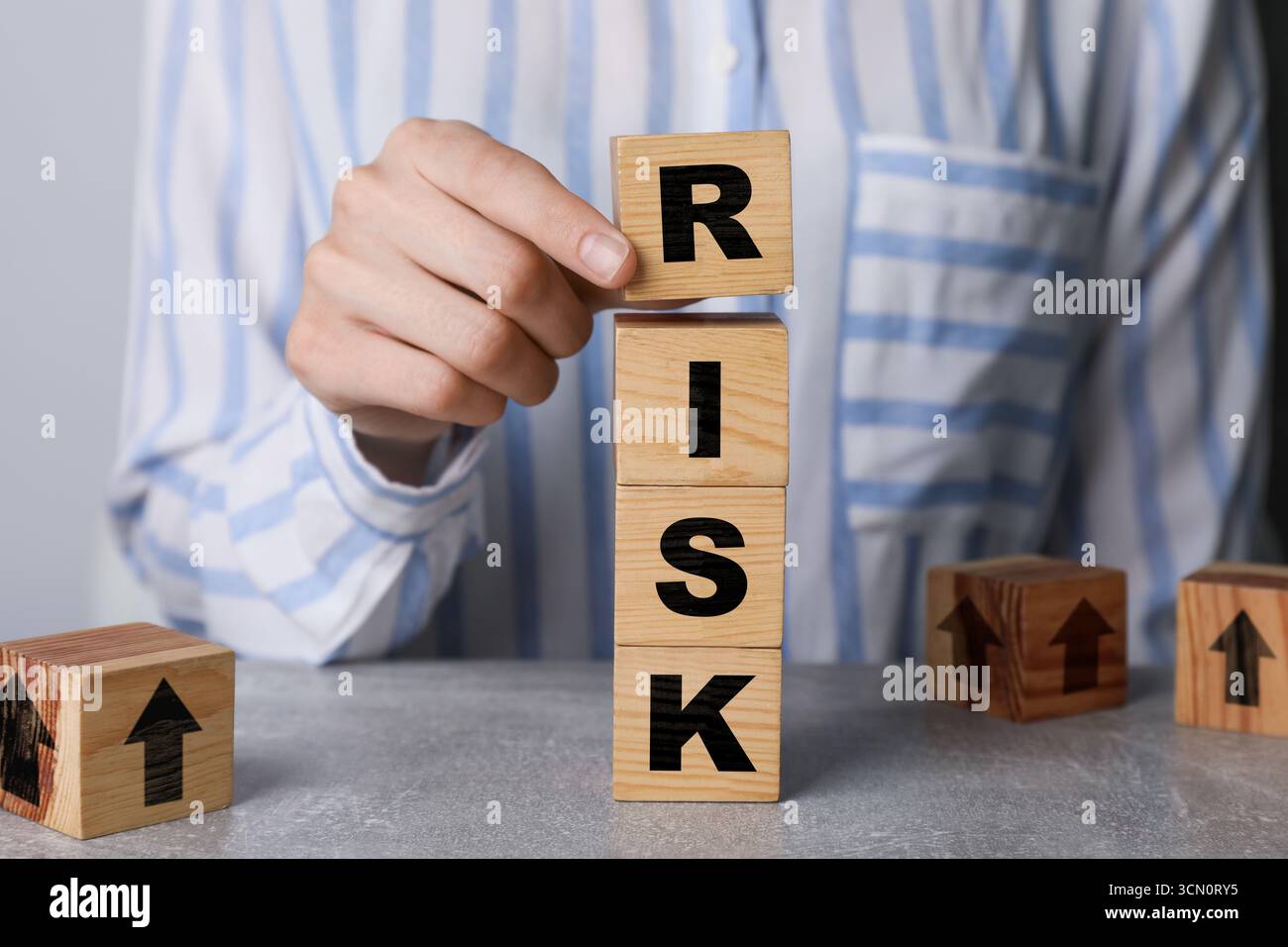 Woman putting wooden cube with letter R to make word Risk at table ...