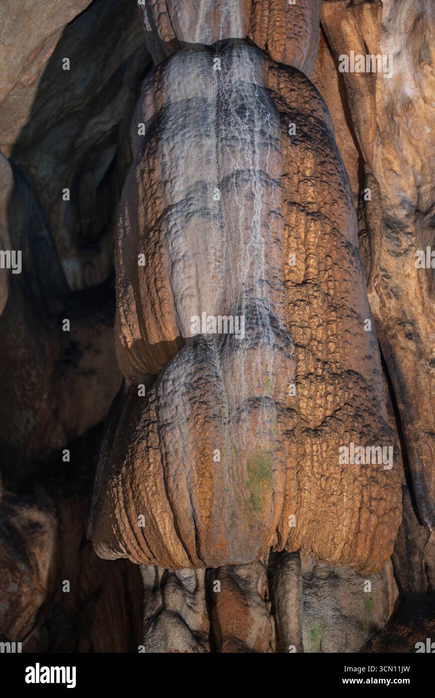 Large flowstone structure inside a limestone cave illuminated by warm ...