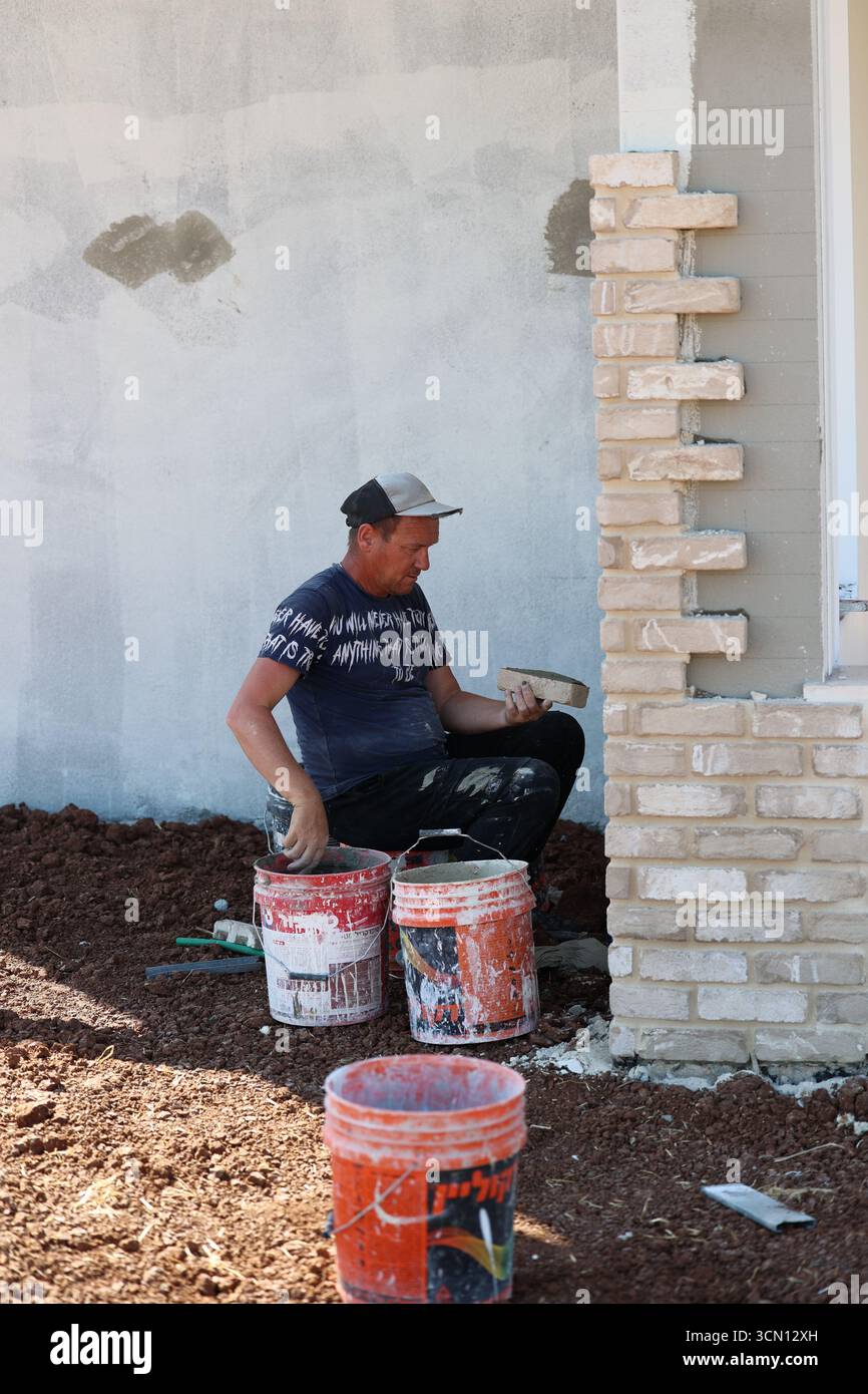 A man working on a brick wall at a construction site Stock Photo