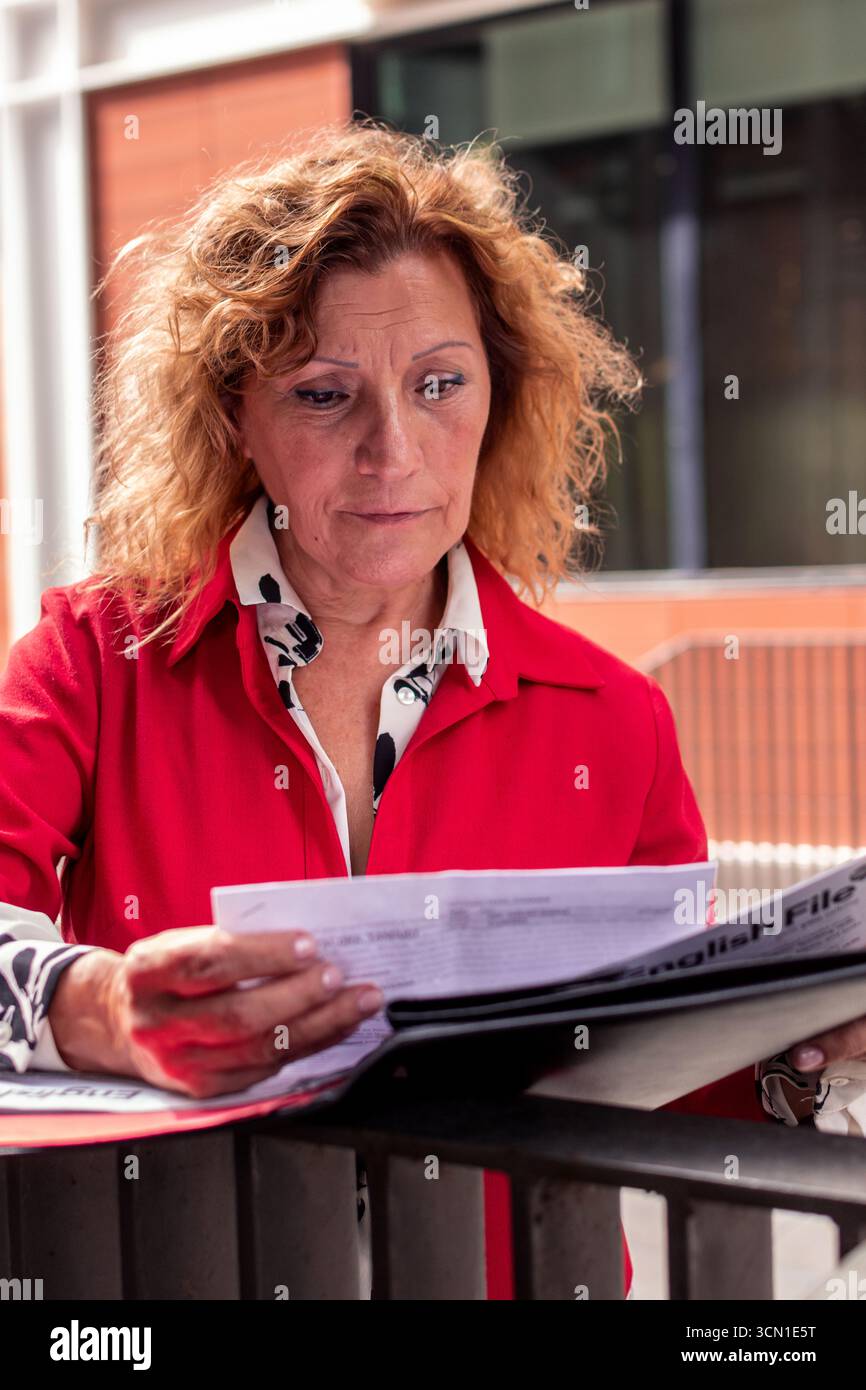 Senior executive woman reading documents outdoors Stock Photo