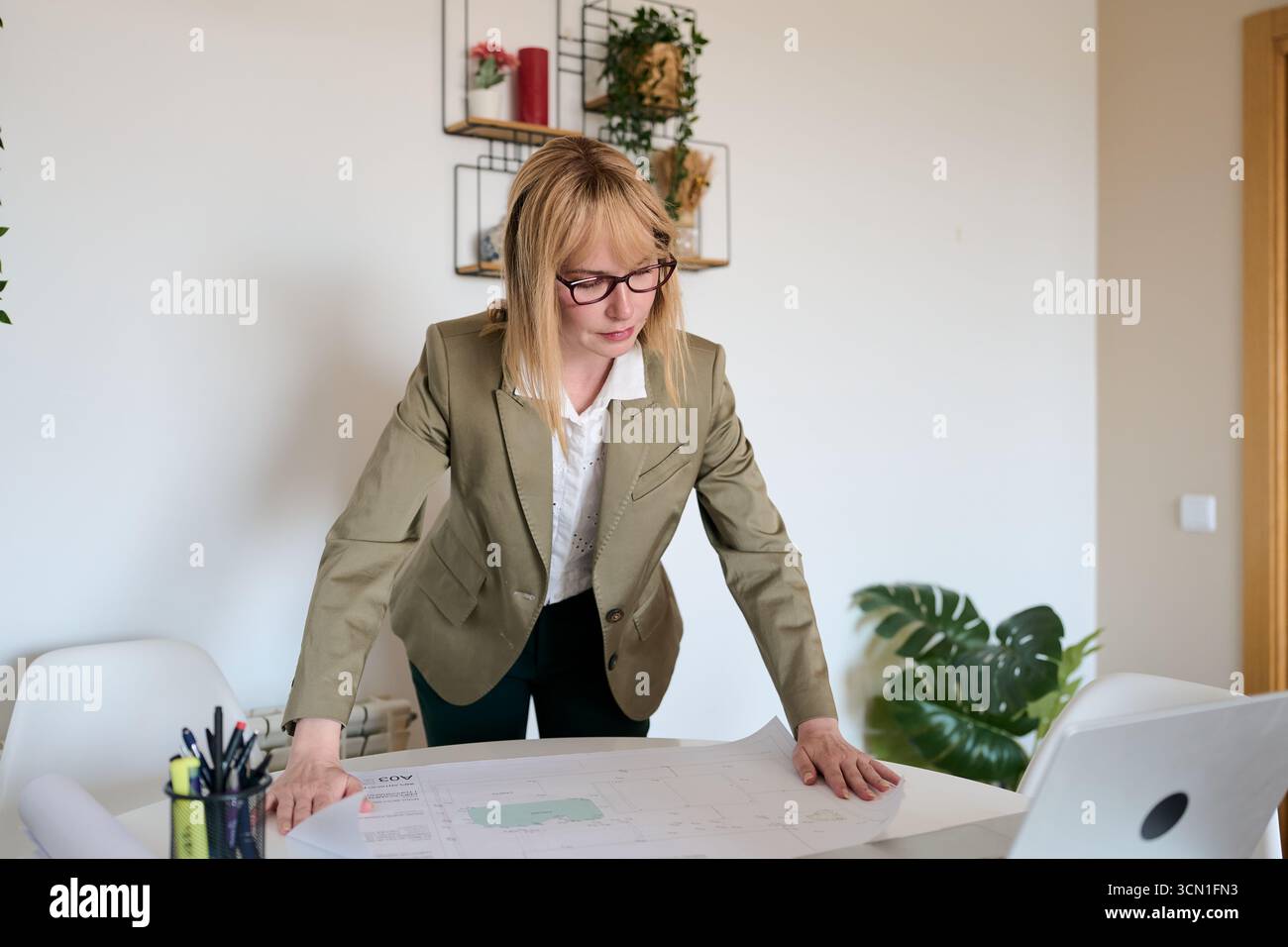 Woman architect analyzing blueprint in home office Stock Photo