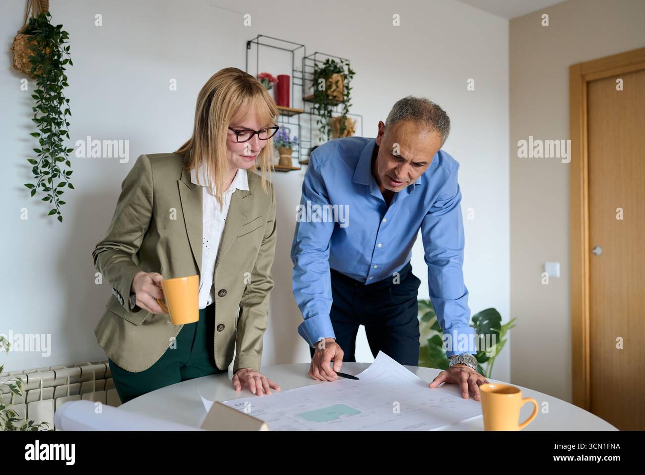 Architects collaborating on building project blueprint in office Stock Photo