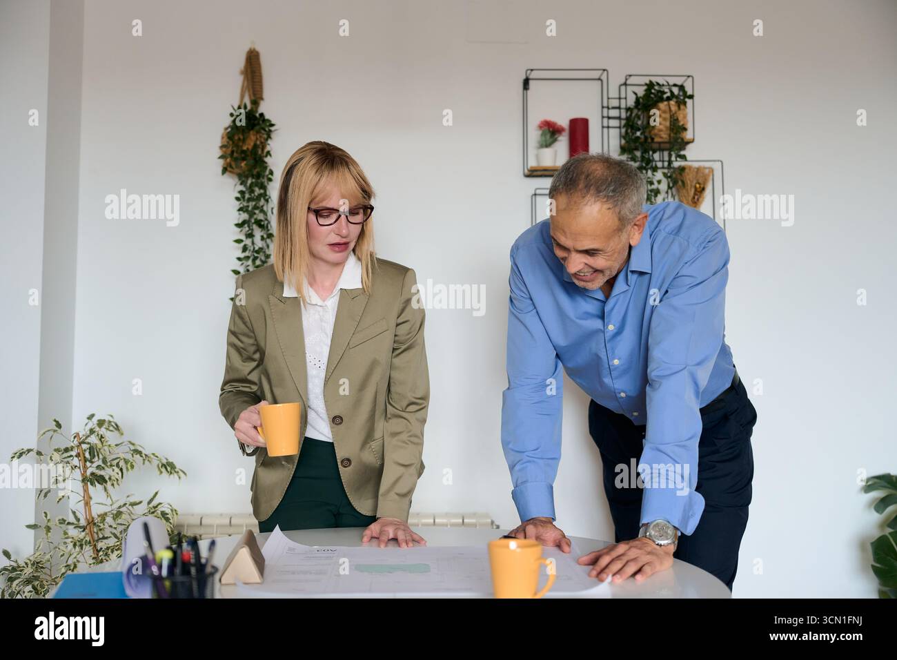 Business colleagues reviewing blueprint for project planning Stock Photo