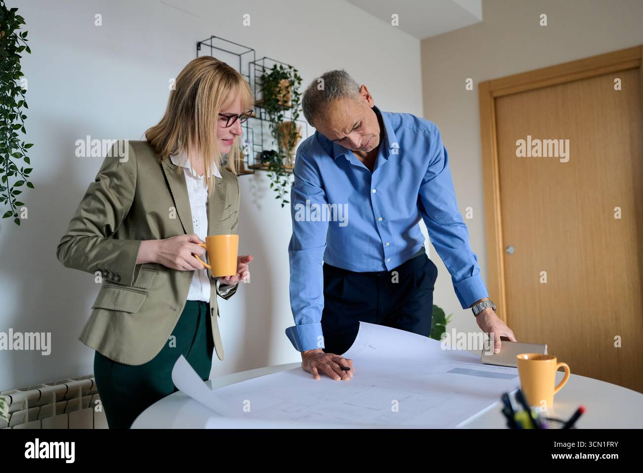 Architects collaborating on building plans in office Stock Photo
