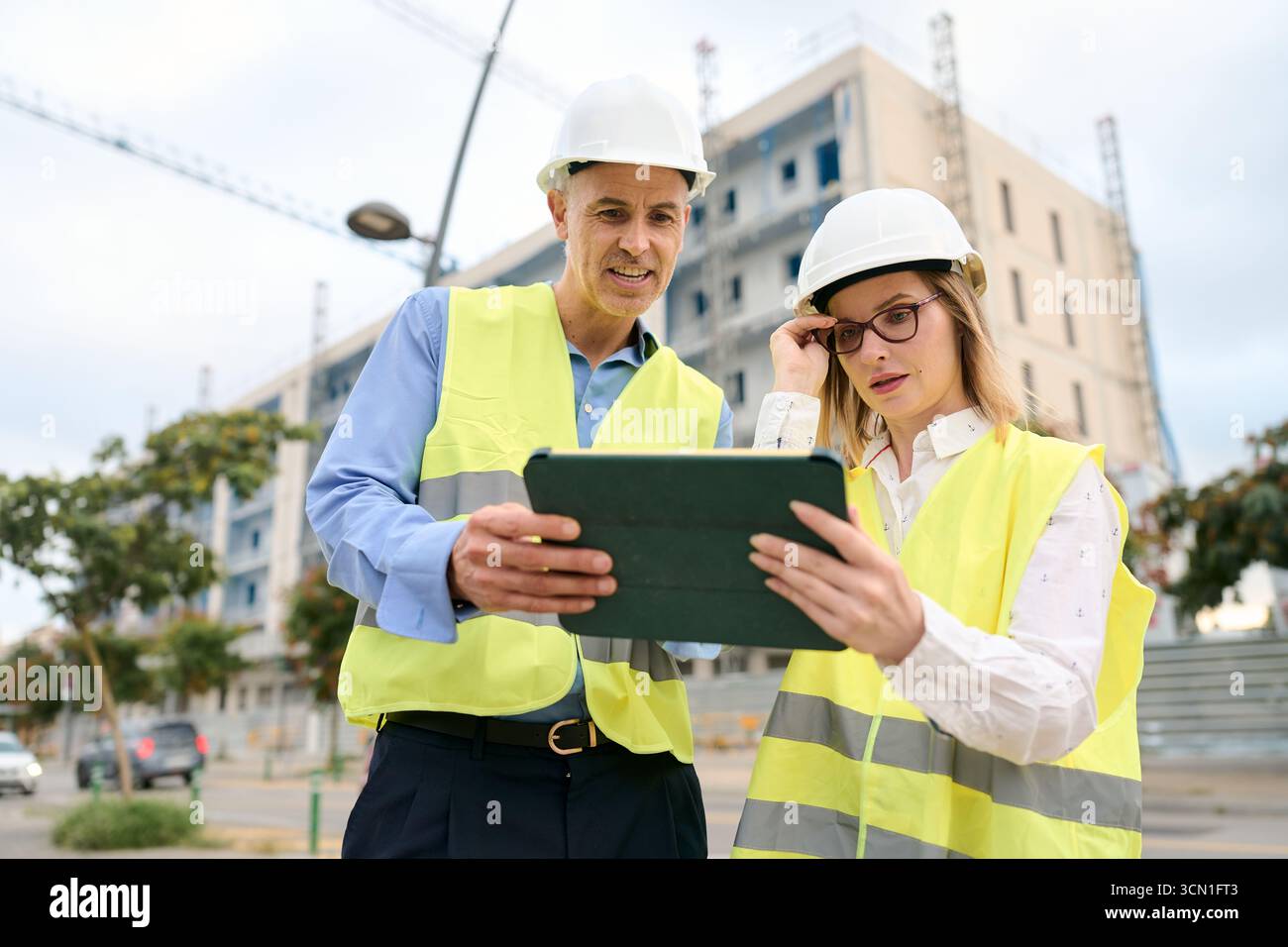 Engineers discussing construction project plans using digital tablet Stock Photo