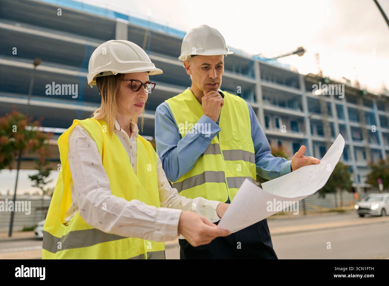 Architects and engineers discussing blueprint at construction site Stock Photo