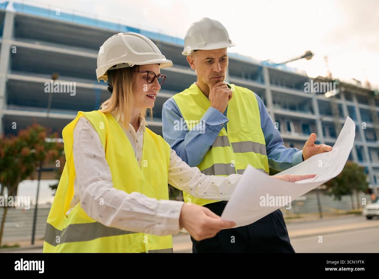 Engineers discussing blueprints at construction site Stock Photo