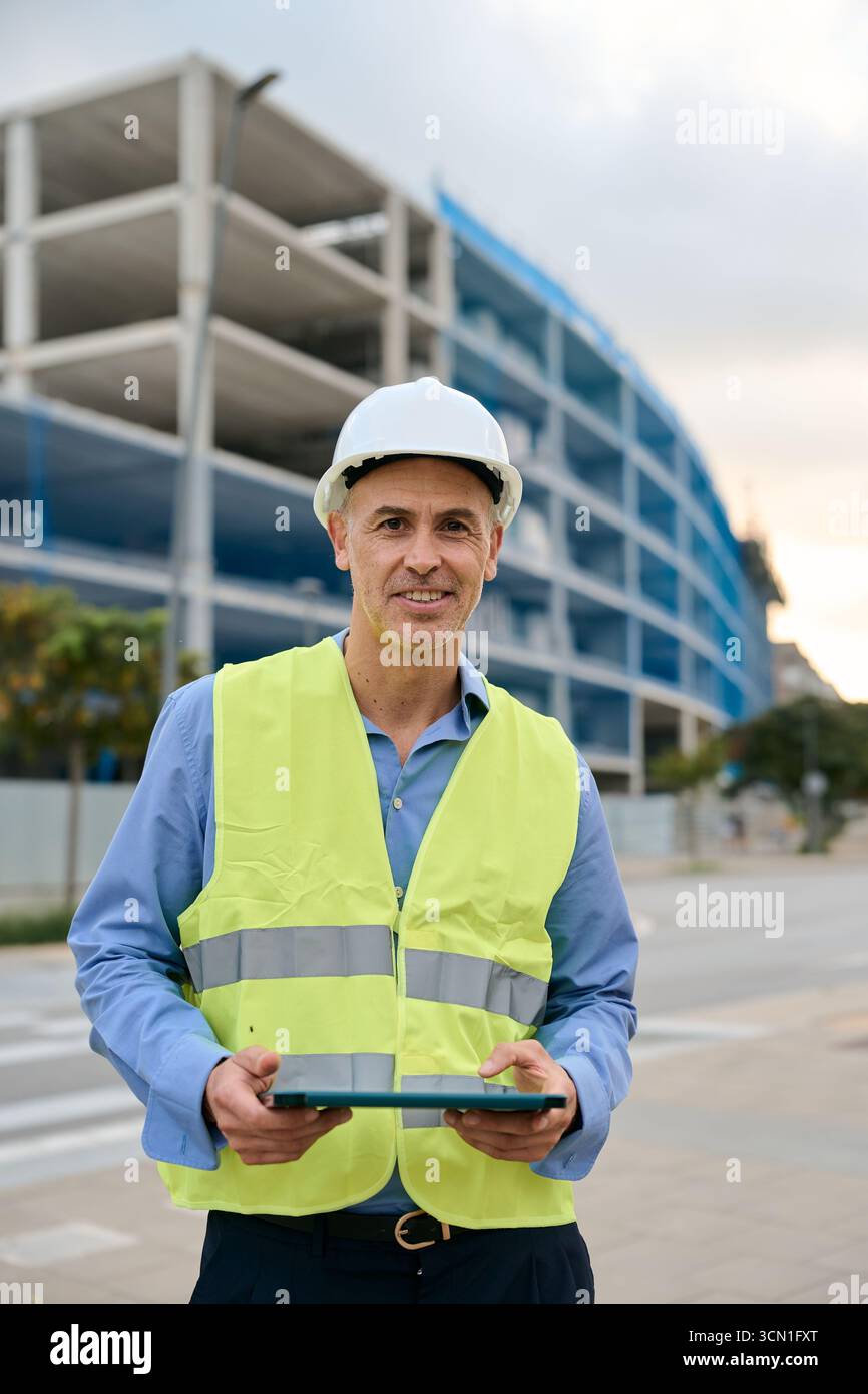 Construction engineer smiling wearing hard hat holding tablet Stock Photo