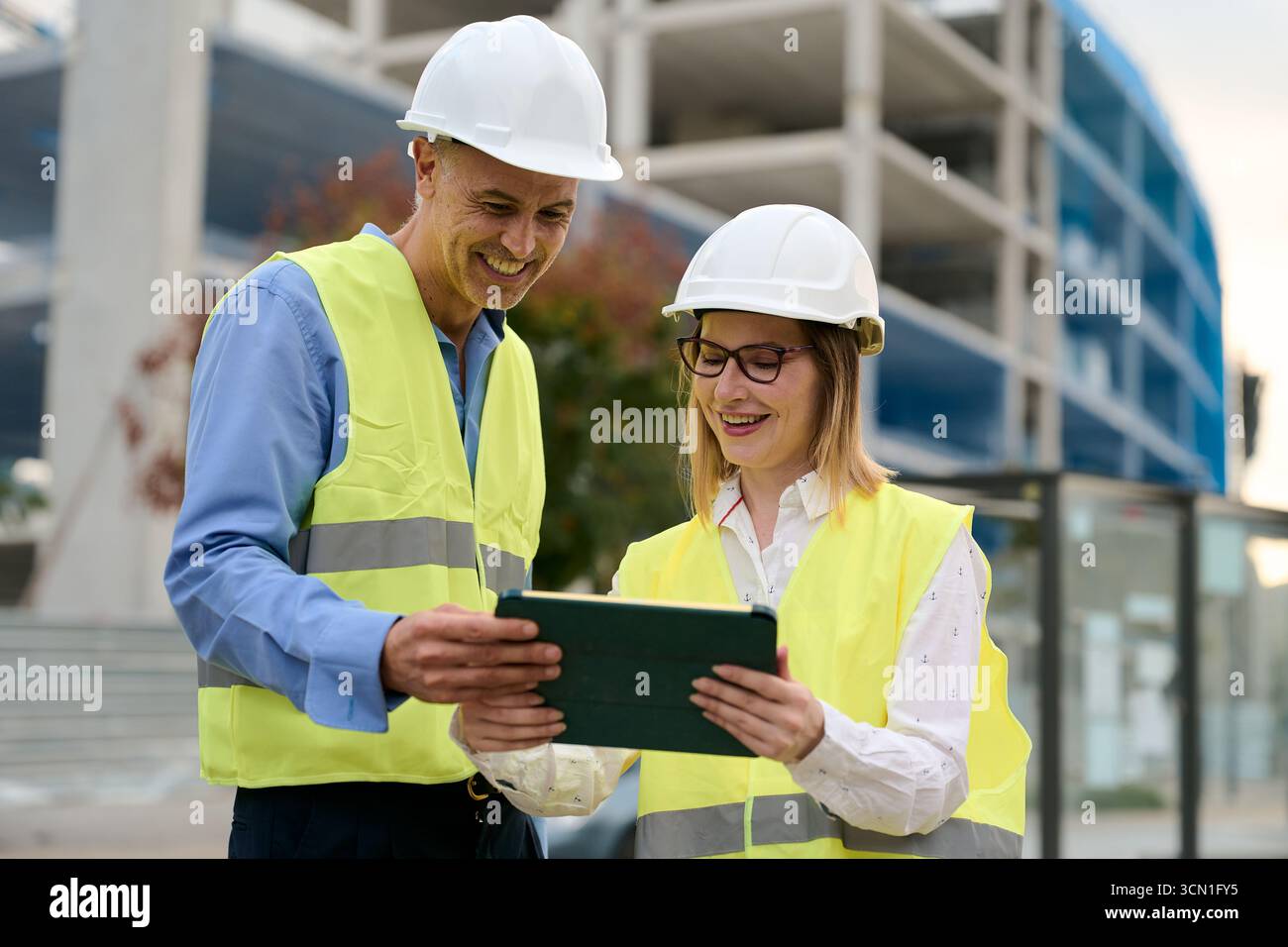 Construction engineers collaborating on building site with tablet Stock Photo