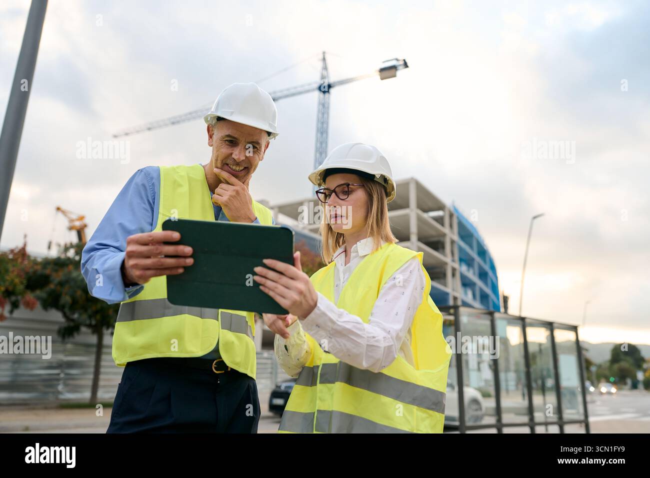 Engineers reviewing construction plans on digital tablet Stock Photo