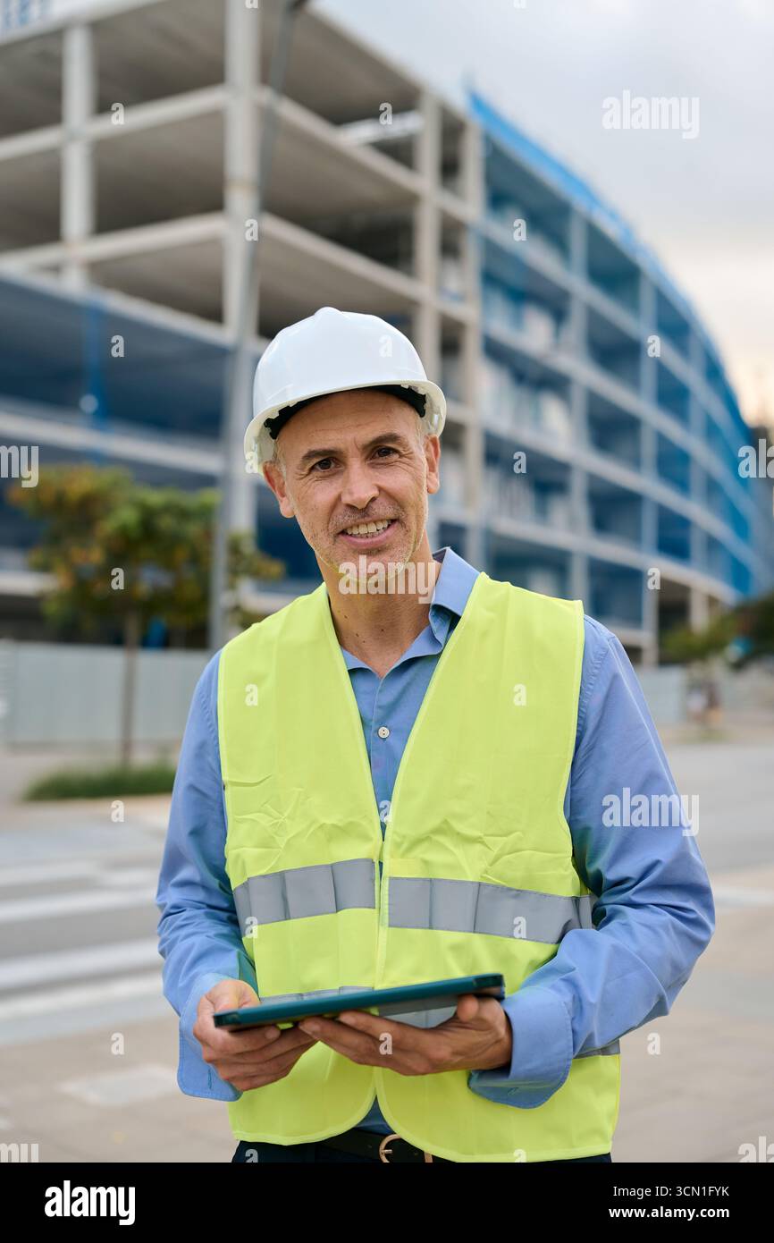 Smiling engineer supervising construction site holding tablet Stock Photo