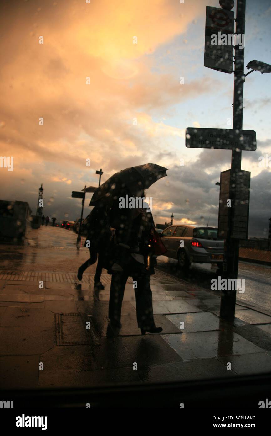 LONDON, UK. 19 OCTOBER, 2010. A pedestrian holds an umbrella in heavy rain on a London bridge, as storm clouds and dramatic skies signal an approachin Stock Photo