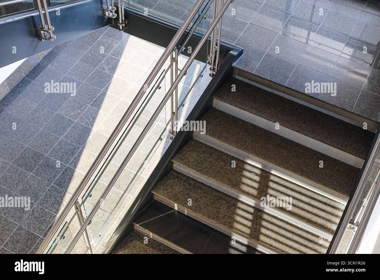 Modern staircase with metal railing. Interior design of office building. Empty steps with sunlight shadow. Architecture detail background. Stock Photo