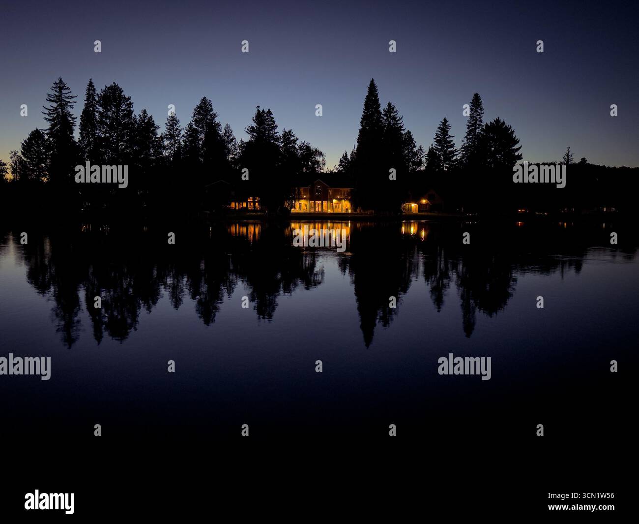 Cabins and Trees Reflected on Lake at Twilight - Smartphone Captured Stock Image