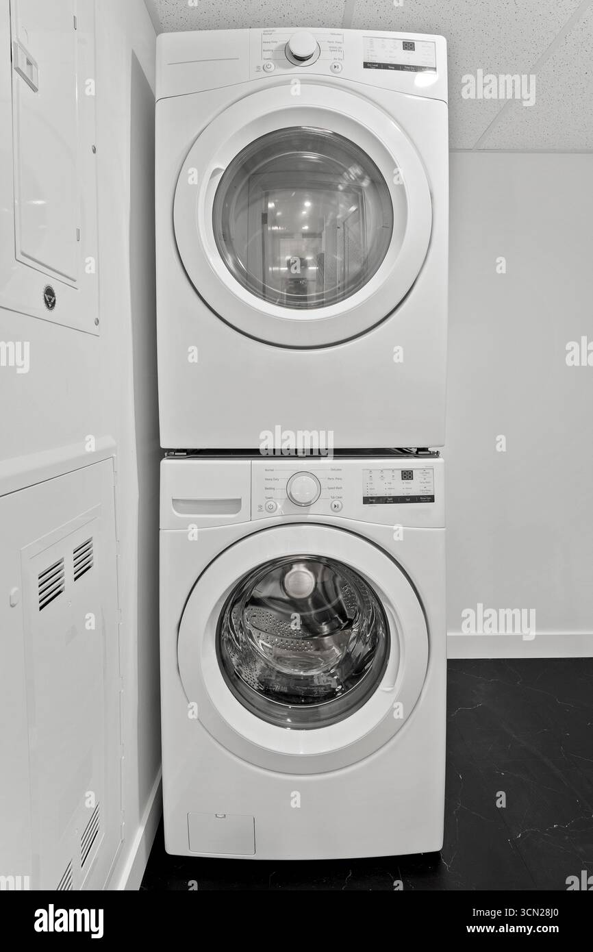 White dryer is stacked on top of another dryer. The dryers are in a ...