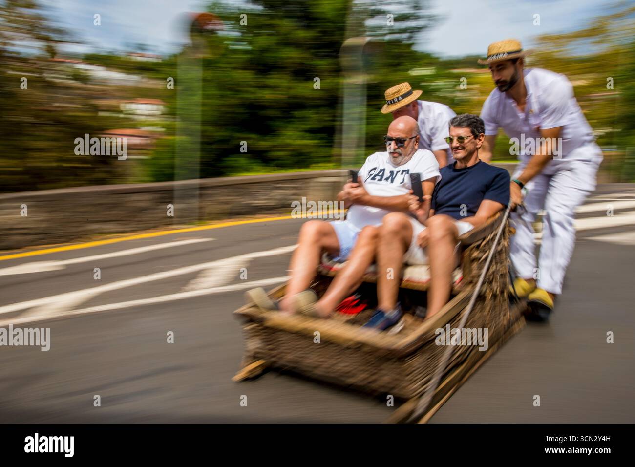 Carreiros guide a Monte Toboggan Ride wicker basket sled ride (Carreiros do Monte), Funchal, Madeira, Portugal. Stock Photo