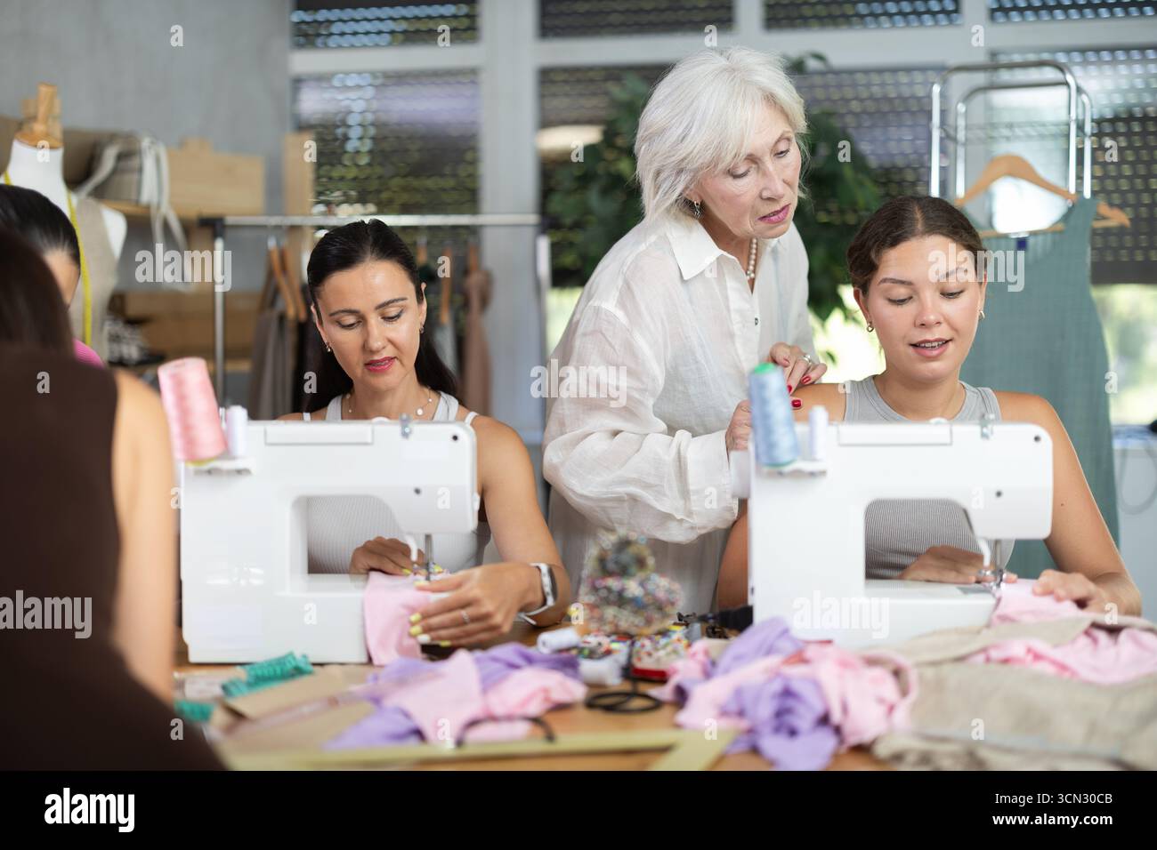 Sewing teacher guiding student during machine work Stock Photo