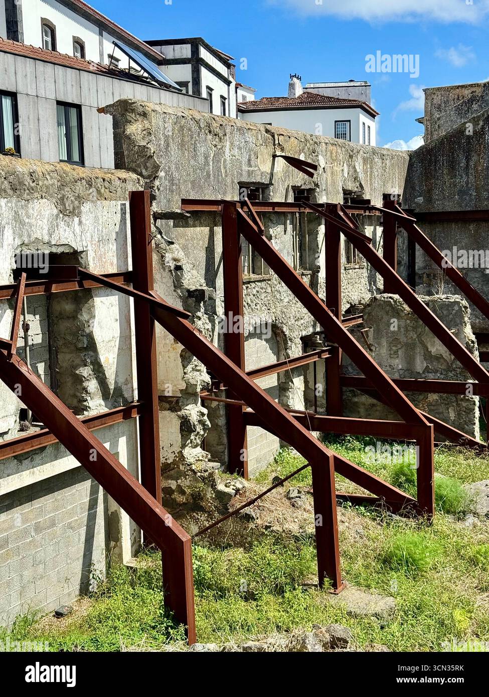 Old building facade supported by metal beams during restoration work in an urban area. - Smartphone Captured Stock Image