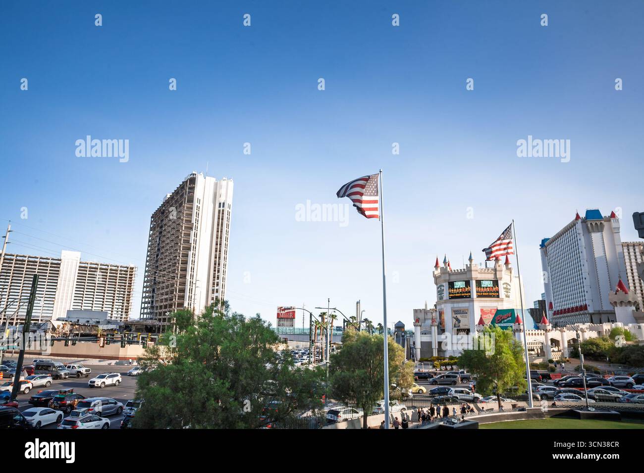 LAS VEGAS - AUGUST 24, 2024: American flags wave by hotels and traffic on the Las Vegas Strip, with the medieval themed Excalibur Hotel and Casino and Stock Photo