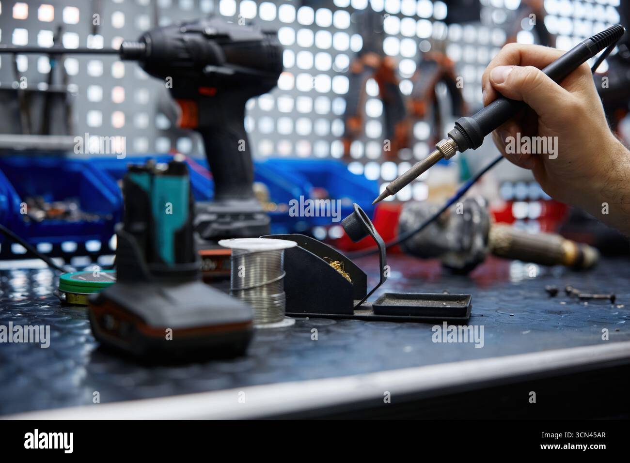 A man using a soldering iron on electronic equipment Stock Photo